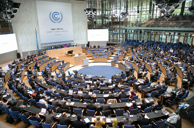 A large conference hall with delegates seated in a circular arrangement, attending the United Nations Climate Change Conference, conveying cooperation and engagement.